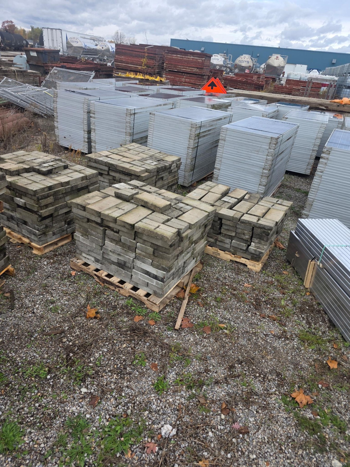 High-angle wide view of an Ontario industrial recovery yard with pallets of stacked solar panels and salvaged materials.